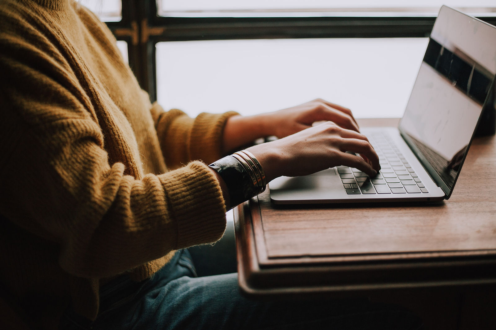 a man writing on a laptop while sitting behind a desk